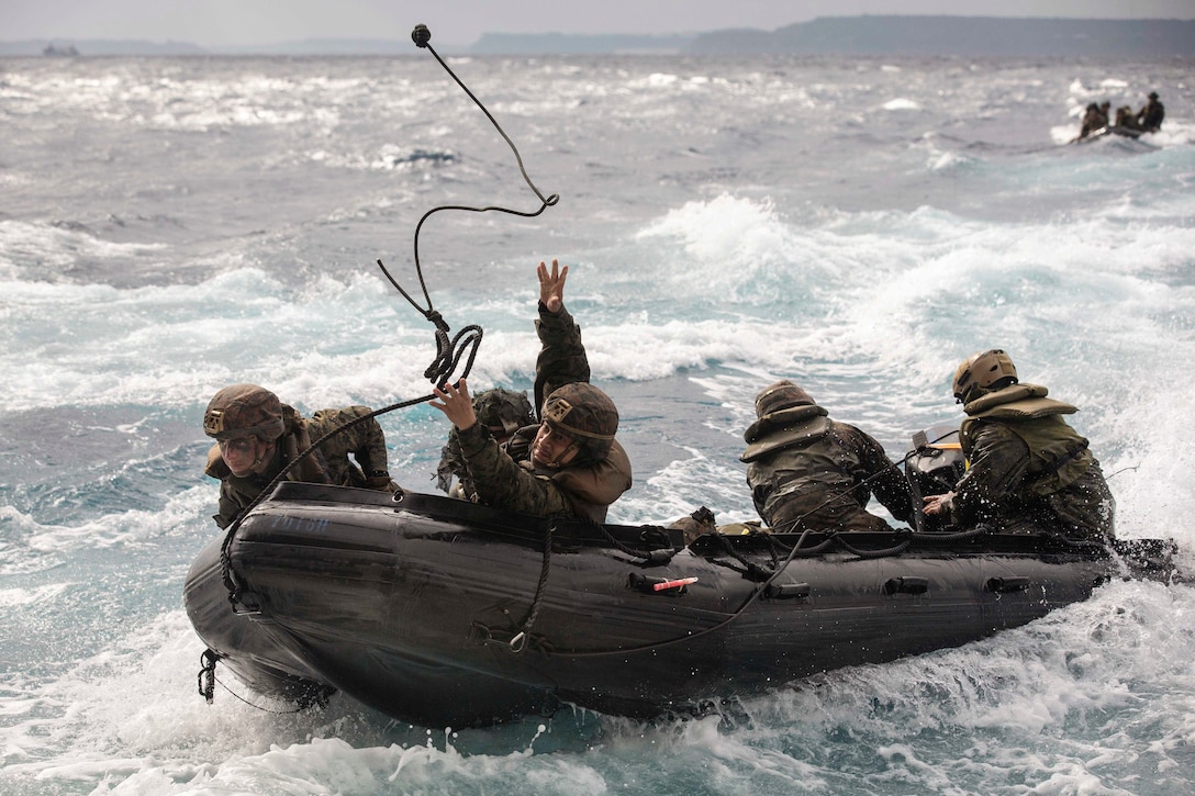 A Marine throws a rope while surrounded by fellow Marines on a boat.