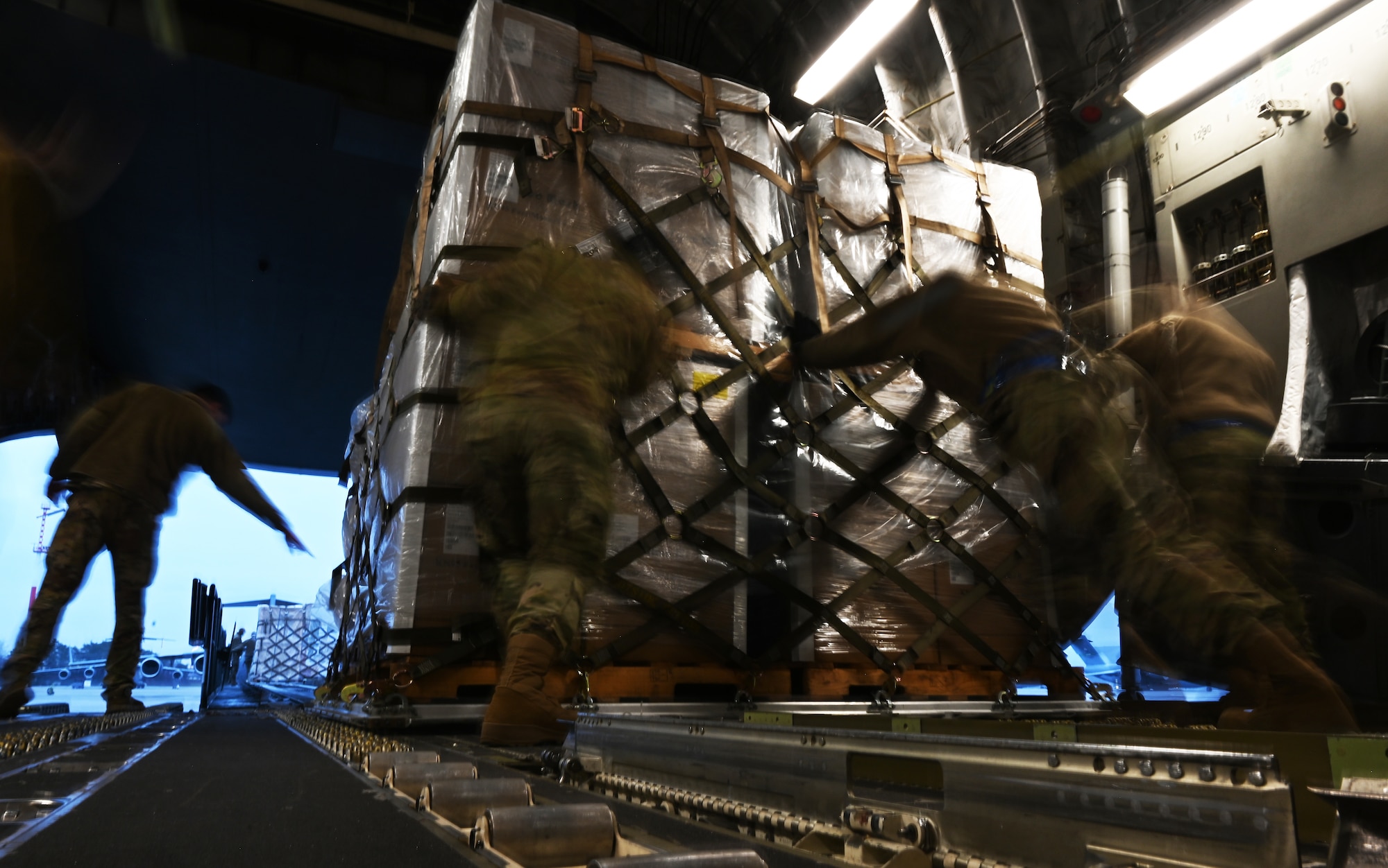 Airmen from the 721st Aerial Port Squadron push a pallet off a C-17 Globemaster III at Ramstein Air Base, Germany, Feb. 2, 2021. Approximately 15 tons of masks were delivered to Ramstein for U.S. military members around Germany to help slow the spread of COVID-19. The 721st APS plays an important role in the distribution of masks and other COVID-19 protective equipment.(U.S. Air Force photo by Senior Airman Thomas Karol)