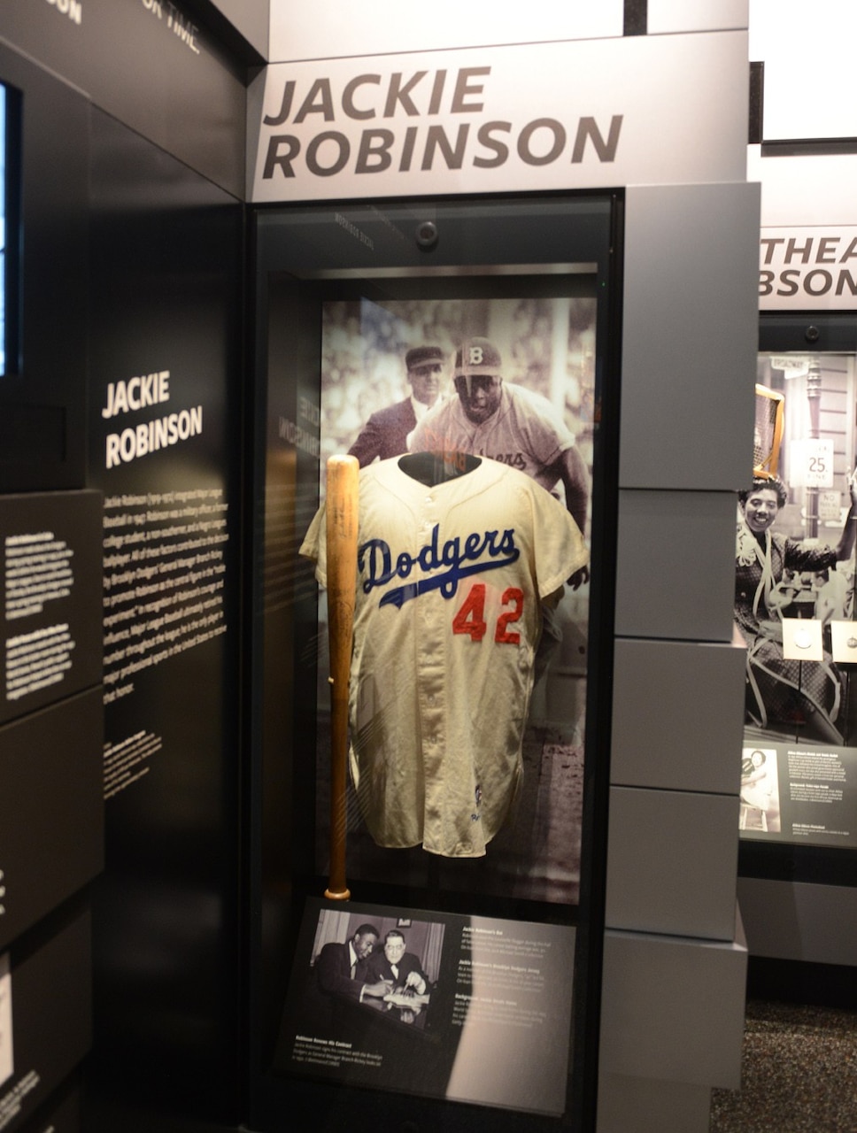A No. 42 baseball jersey with the name Dodgers splashed across the front is on display in a museum case.