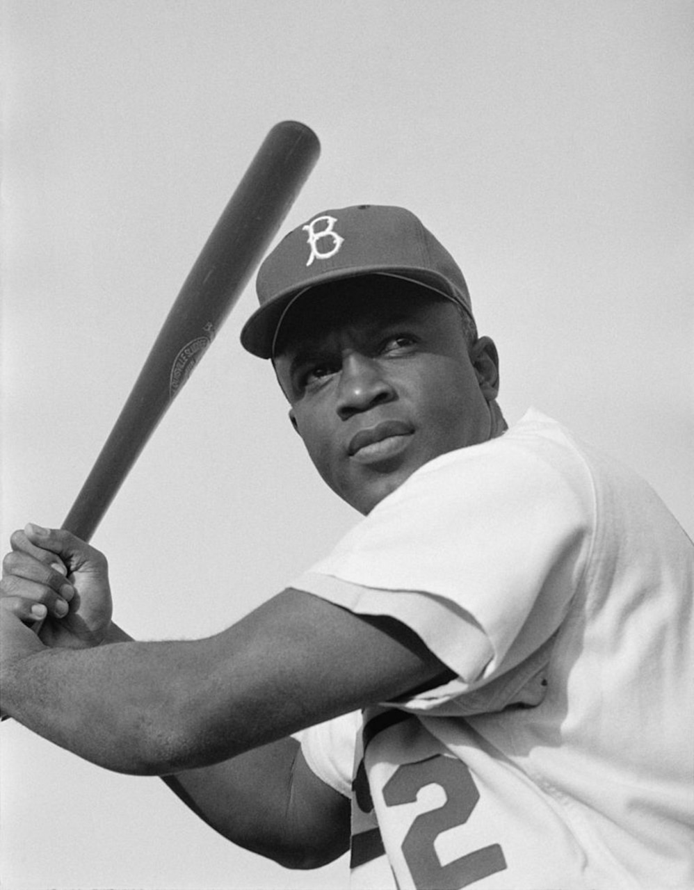 A baseball player, holding a bat, poses for a photo.