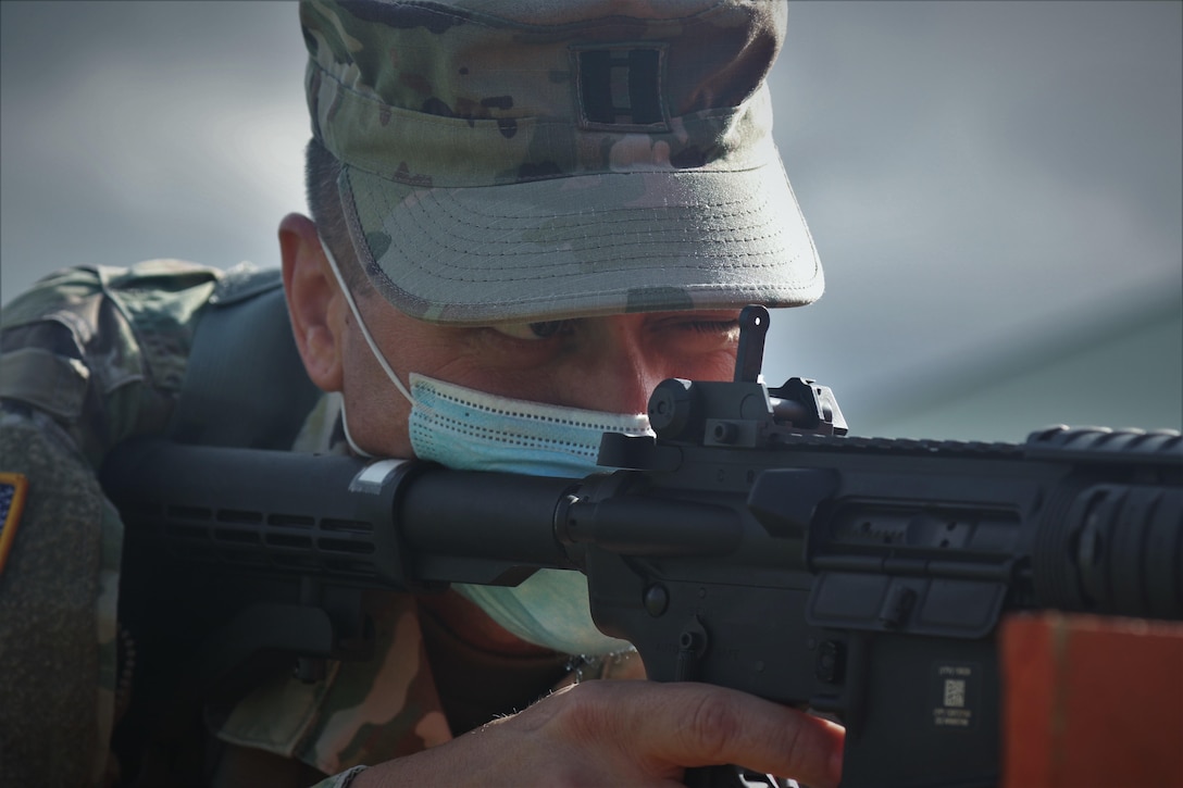 A man in uniform aims a weapon.