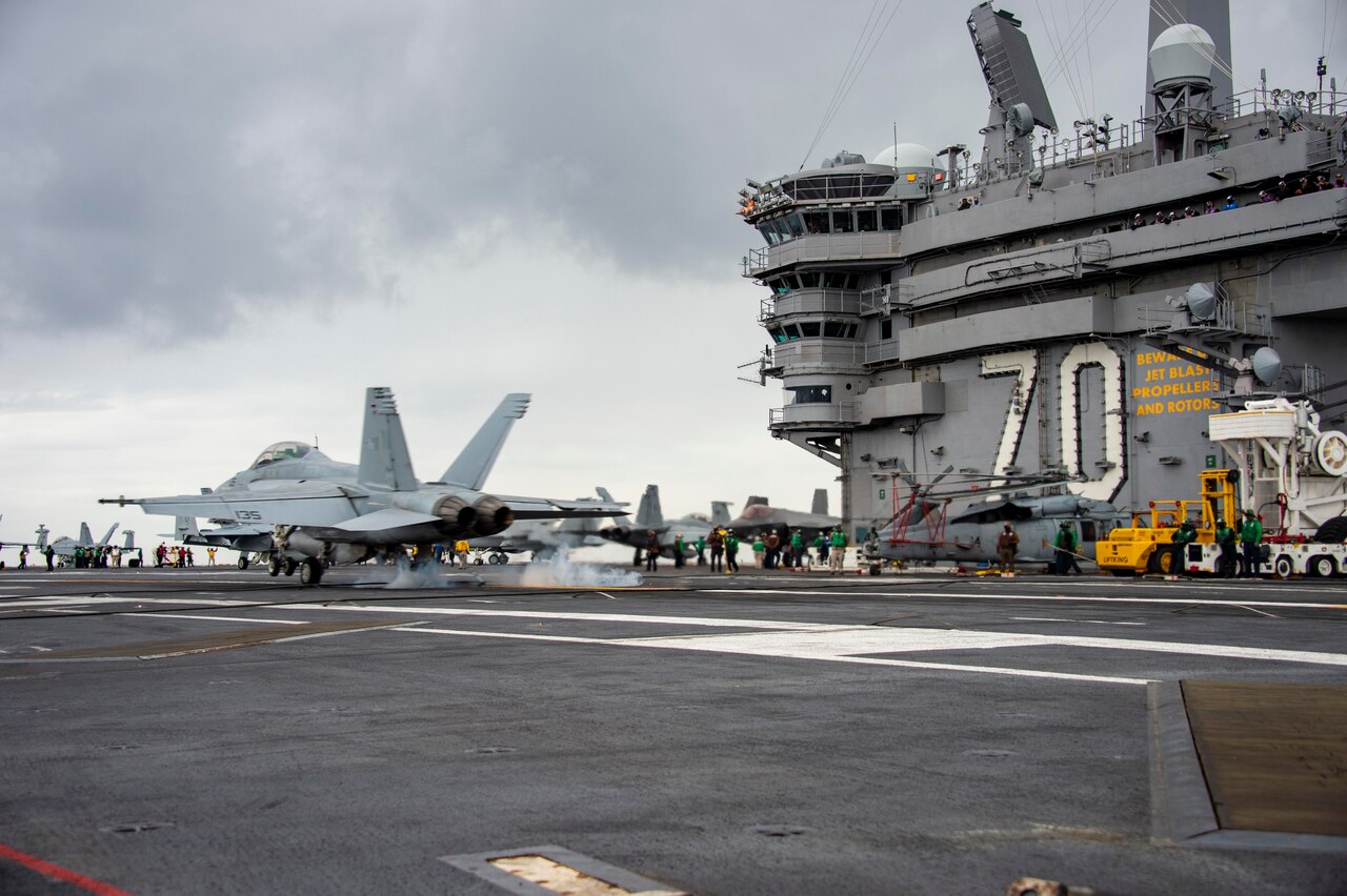 A jet lands on an aircraft carrier.