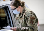 Staff Sgt. Melinda Grounds, a medic with the 141st Medical Group and a registered nurse in Idaho, goes through a questionnaire with a visitor to the mass vaccination site at the Clark County Fairgrounds in Ridgefield, Wash., Jan. 28, 2021. The Washington National Guard is helping at four vaccination sites.