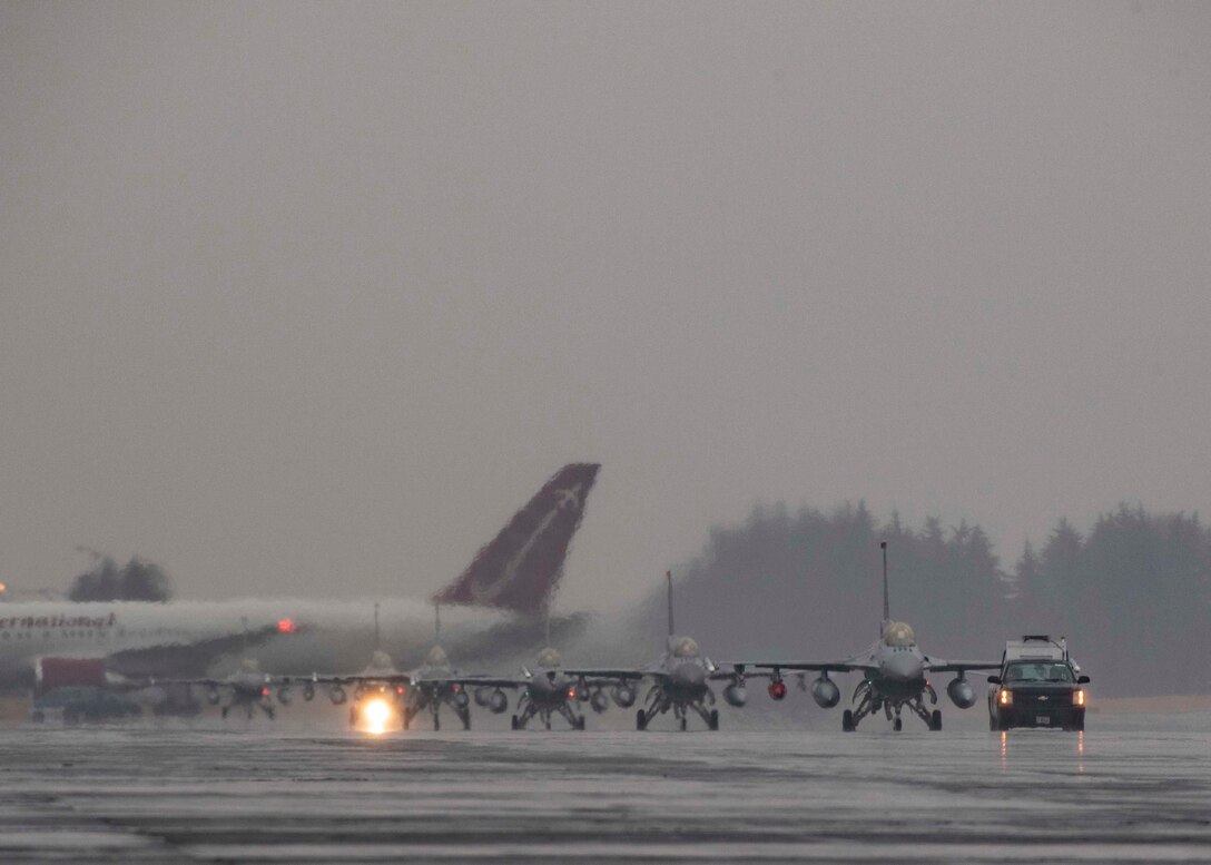 Low angle of five F-16's coming up the flightline.