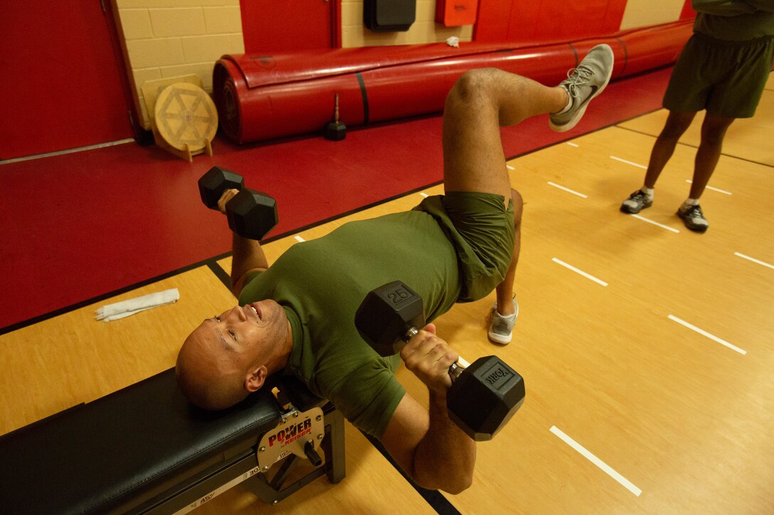 U.S. Marine Corps Staff Sgt. Caleb King, a Postal Chief with the Wounded Warrior Battalion East Detachment, demonstrates alternative ways to make lifting weights more challenging during the High Intensity Tactical Training (HITT) course in the Hopkins Gymnasium on Camp Elmore, Norfolk, Virginia, January 27, 2021. HITT is a comprehensive strength and conditioning program that focuses on maintaining and improving physical resiliency and combat readiness. The Marines that progressed through the course will be a knowledgeable resource for physical training (PT) and will be able to conduct PT properly within their respective units. (U.S. Marine Corps Photo by Lance Cpl. Jack Chen/released)