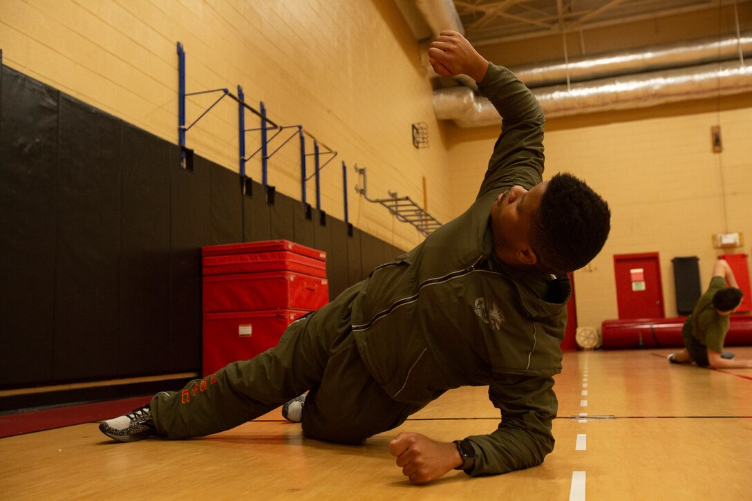 U.S. Marine Corps Sgt. Adam A. Chandler, an Academics Instructor at the Naval School of Music, performs a proper stretch during the High Intensity Tactical Training (HITT) course in the Hopkins Gymnasium on Camp Elmore, Norfolk, Virginia, January 26, 2021. HITT is a comprehensive strength and conditioning program that focuses on maintaining and improving physical resiliency and combat readiness. The Marines that progressed through the course will be a knowledgeable resource for physical training (PT) and will be able to conduct PT properly within their respective units. (U.S. Marine Corps Photo by Lance Cpl. Jack Chen/released)