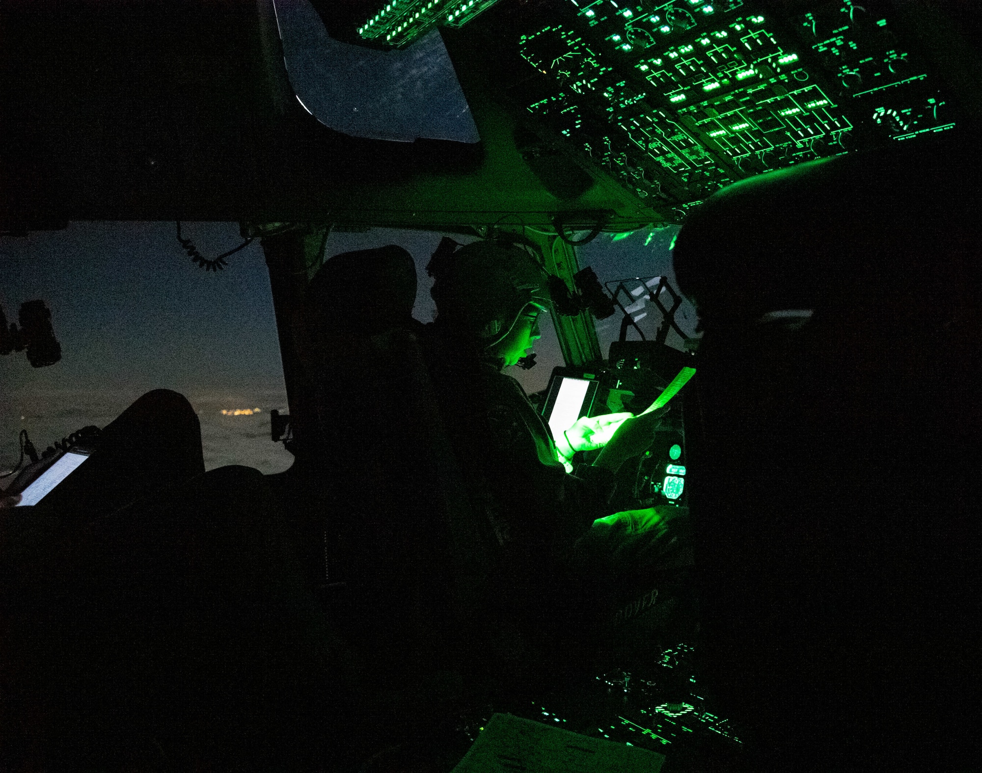 Capt. Sarah Aravich, 3rd Airlift Squadron pilot, views a map during a low-light training sortie on a C-17 Globemaster III, over Pennsylvania, Jan. 28, 2021. In combat, flying at night without artificial light minimizes visibility of the aircraft and reduces threat from potential enemies. The 3rd AS routinely trains to support global engagement through direct delivery of time-critical theater deployment assets and ensure aircrew operational readiness. (U.S. Air Force photo by Airman 1st Class Faith Schaefer)