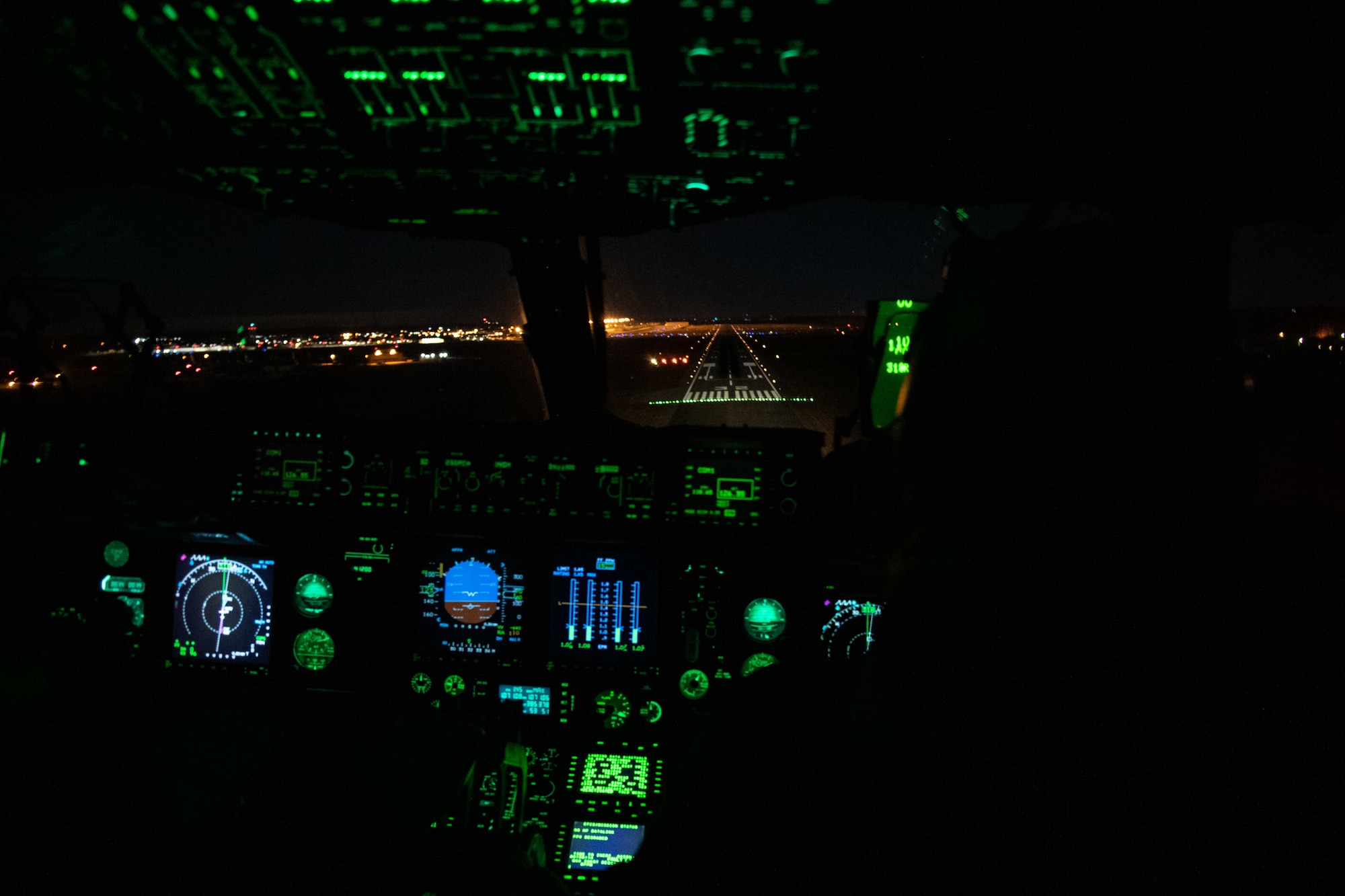 1st Lt. Zachary Pruitt, 3rd Airlift Squadron pilot, and Capt. Corey Landis, 3rd AS instructor pilot, prepare to land a C-17 Globemaster III, while wearing night vision goggles, at Dover Air Force Base, Delaware, Jan. 28, 2021. In combat, flying at night without artificial light minimizes visibility of the aircraft and reduces threat from potential enemies. The 3rd AS routinely trains to support global engagement through direct delivery of time-critical theater deployment assets and ensure aircrew operational readiness. (U.S. Air Force photo by Airman 1st Class Faith Schaefer)