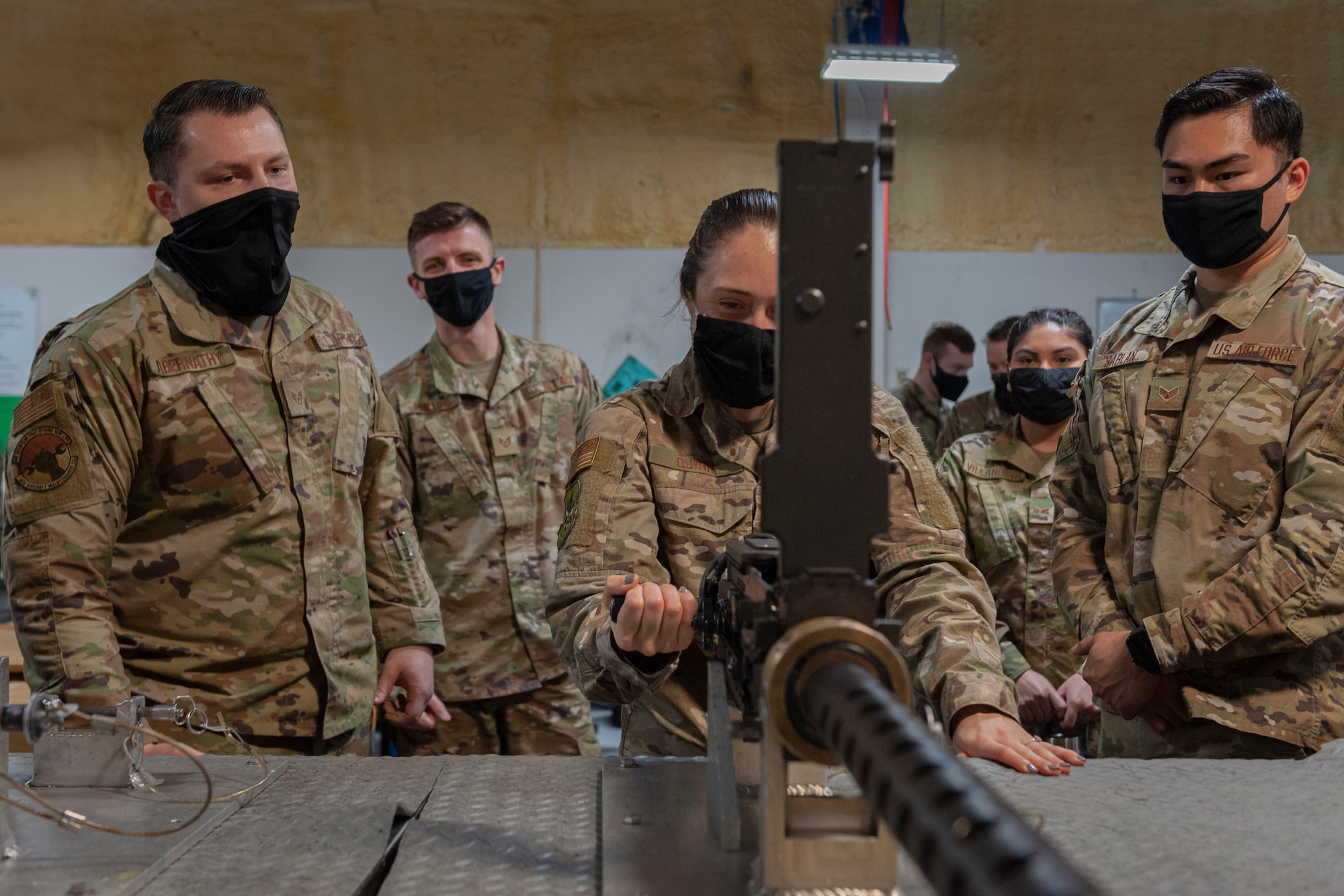 Photo of an Airman pulling a charging handle on an M2 machine gun