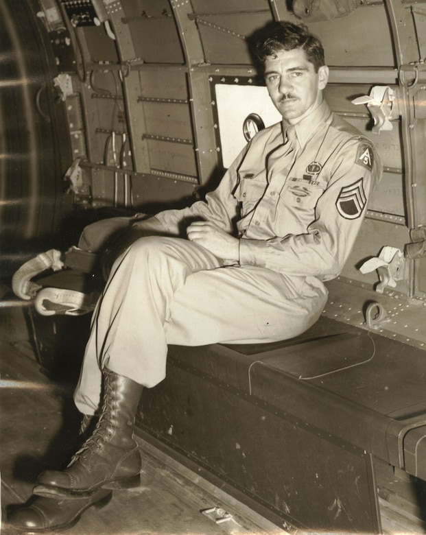 A man with his legs crossed sits in the cargo hold of a plane.