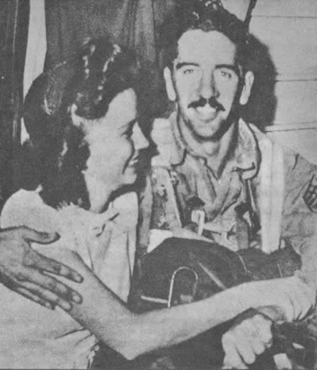 A man sits with his arm around a smiling woman.