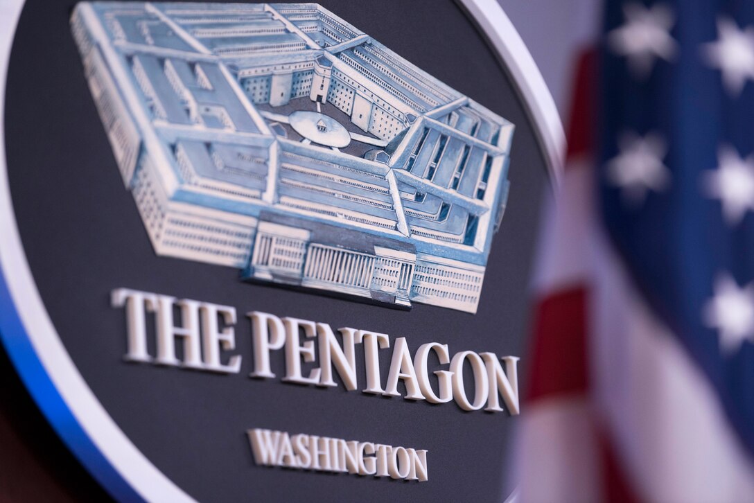 A Pentagon seal hangs on a wall.