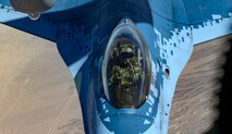 Pilot in the cockpit of fighter jet during aerial refueling.