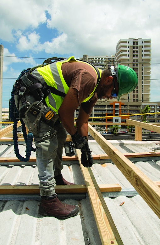 A Contractor for the Corps of Engineers in Puerto Rico works on the first install of a first Blue Roof on the Multy Medical Facilities in San Juan. Having the roof protected will allow the hospital to open up additional patient beds/rooms that were previously unavailable because of the damaged roof.