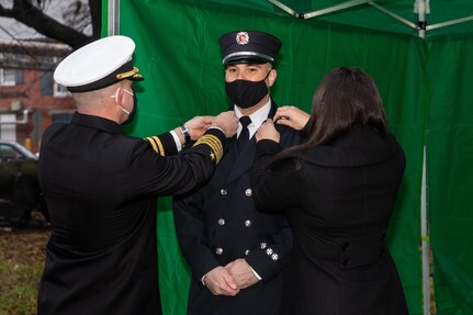 Captain Jeremy Brown is being pinned by his wife Dana Brown and Captain Jason Schneider, Commanding Officer, Naval Weapons Station Yorktown, during a promotion ceremony at Norfolk Naval Shipyard’s (NNSY) Trophy Park on Monday, Feb. 1. Captain Brown is one of five newly promoted captains assigned to NNSY and Naval Weapons Station Yorktown, Fire District 2.