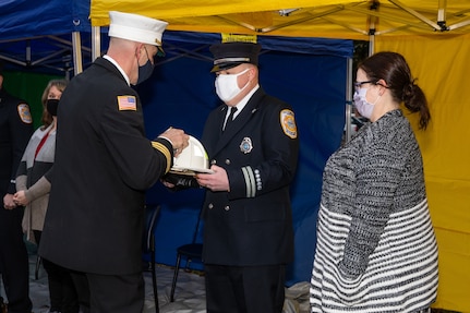 Commander Navy Region Mid-Atlantic, Fire Chief, Kevin Janney presents Captain Joshua Tomon with his new captain’s fire helmet during a promotion ceremony at Norfolk Naval Shipyard’s (NNSY) Trophy Park on Monday, Feb. 1. This presentation is a fire department tradition that has accompanied promotions for decades. Captain Tomon is accompanied by his wife Laura Tomon and is one of five newly promoted captains assigned to NNSY and Naval Weapons Station Yorktown, Fire District 2.