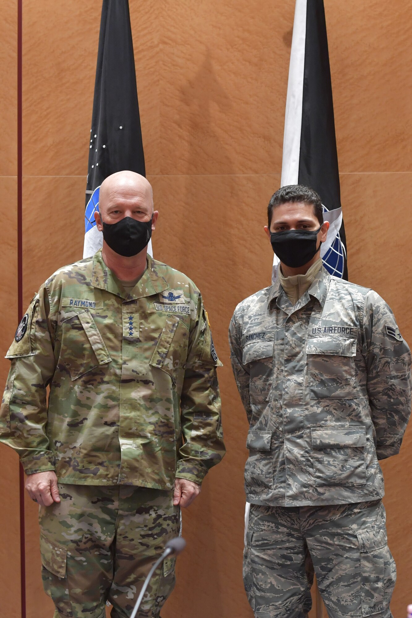 Guardian and Airman standing in front of U.S. Space Force flags.