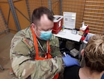Army Capt. Ronald Smith, a physician’s assistant with the Michigan National Guard’s 1119th Field Artillery Regiment, administers a COVID-19 vaccination at the Lansing Mall clinic.