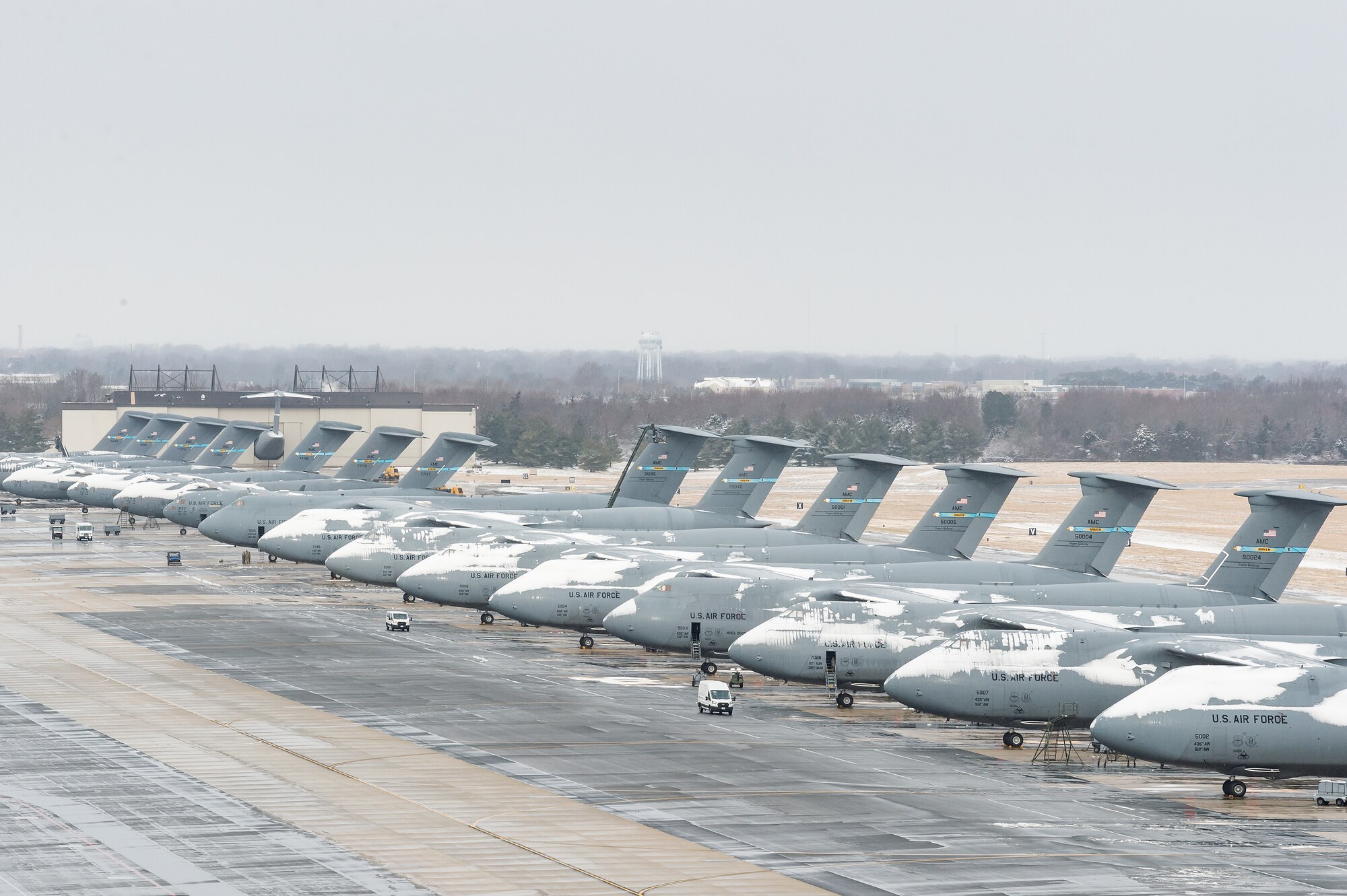 A view from the air traffic control tower of C-5M Super Galaxy and C-17 Globemaster III aircraft parked on the flight line after a nor’easter to produced snow showers at Dover Air Force Base, Delaware, Feb. 2, 2021. As snow fell, the base continued normal operations and prepared for additional forecast snowfall during the next day. (U.S. Air Force photo by Roland Balik)