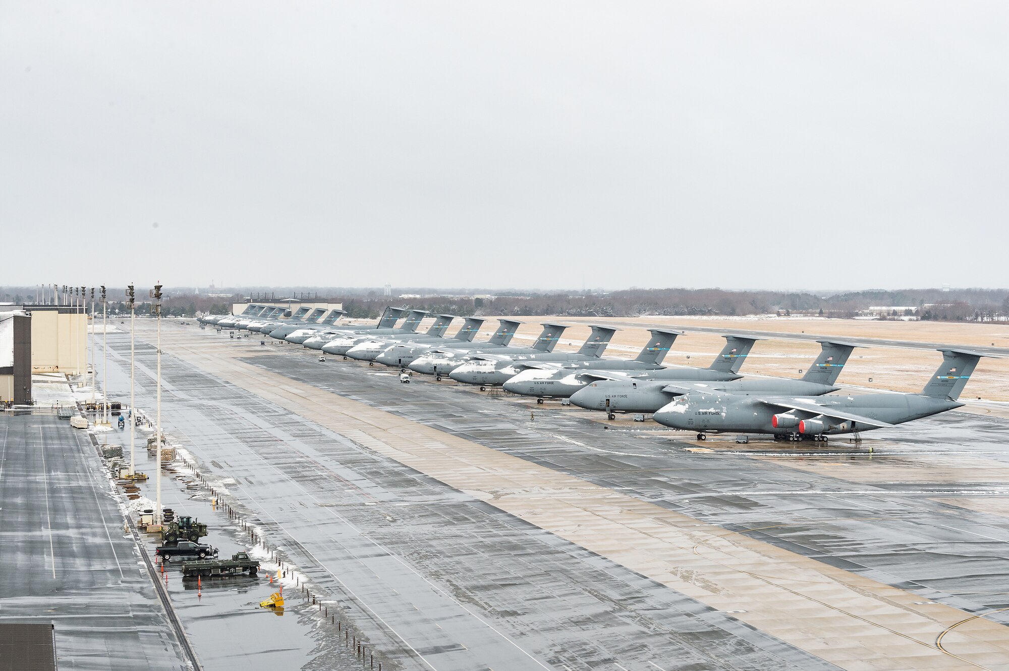 A view from the air traffic control tower of C-5M Super Galaxy and C-17 Globemaster III aircraft parked on the flight line after a nor’easter to produced snow showers at Dover Air Force Base, Delaware, Feb. 2, 2021. As snow fell, the base continued normal operations and prepared for additional forecast snowfall during the next day. (U.S. Air Force photo by Roland Balik)