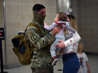 Corinna Treviño and son Ezra welcome Staff Sgt. Marco Treviño, 433rd Security Forces Squadron, home at the San Antonio airport Jan. 31, 2021. Treviño and several other squadron members completed a six-month deployment to provide base security at a location in Southwest Asia. (U.S. Air Force photo by Master Sgt. Kristian Carter)