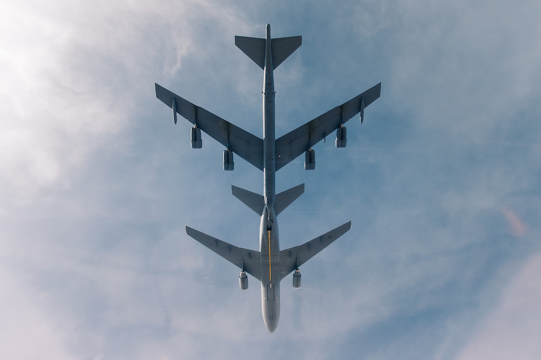 A large aircraft flies close to a second large aircraft.