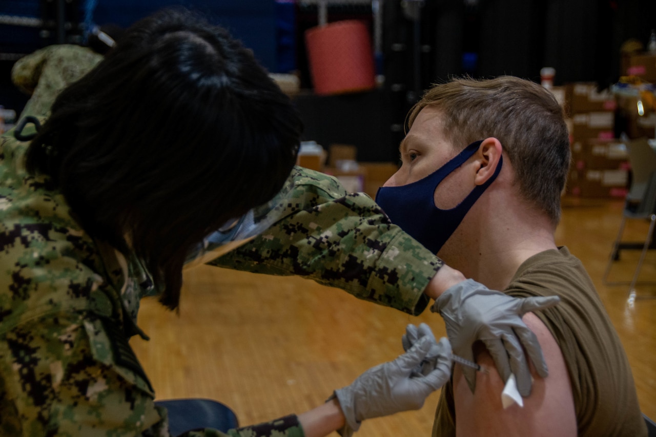 A sailor receives a vaccine shot in the arm.