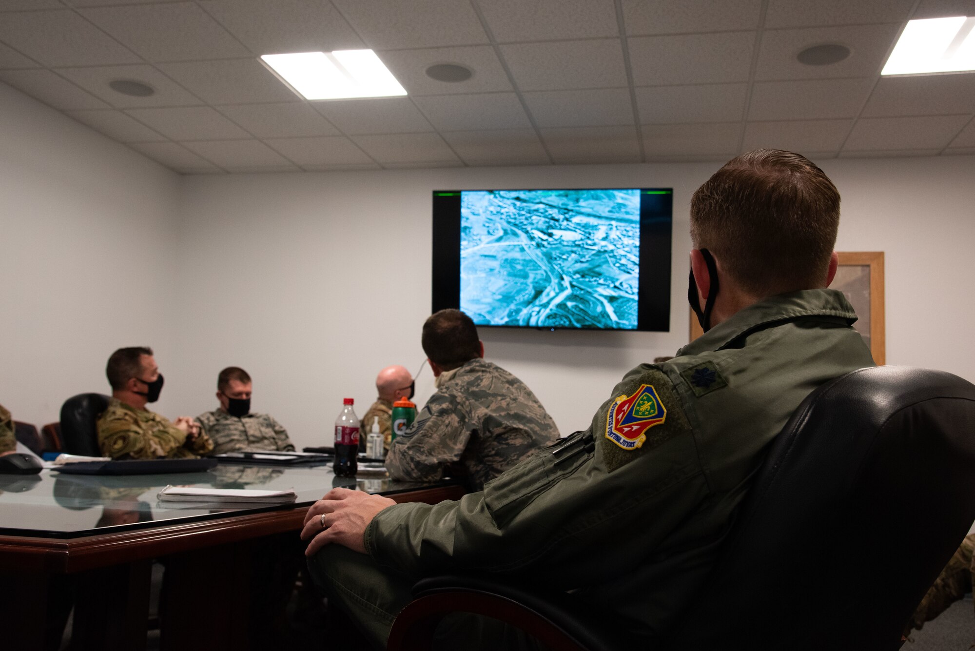 Airmen sit in a room and look at a screen. They are sitting in on a virtual staff ride.