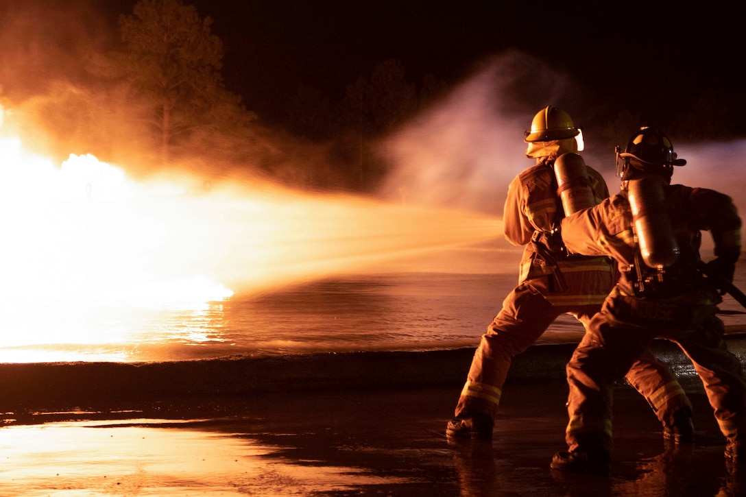 Marines use a water hose to put out a fire.