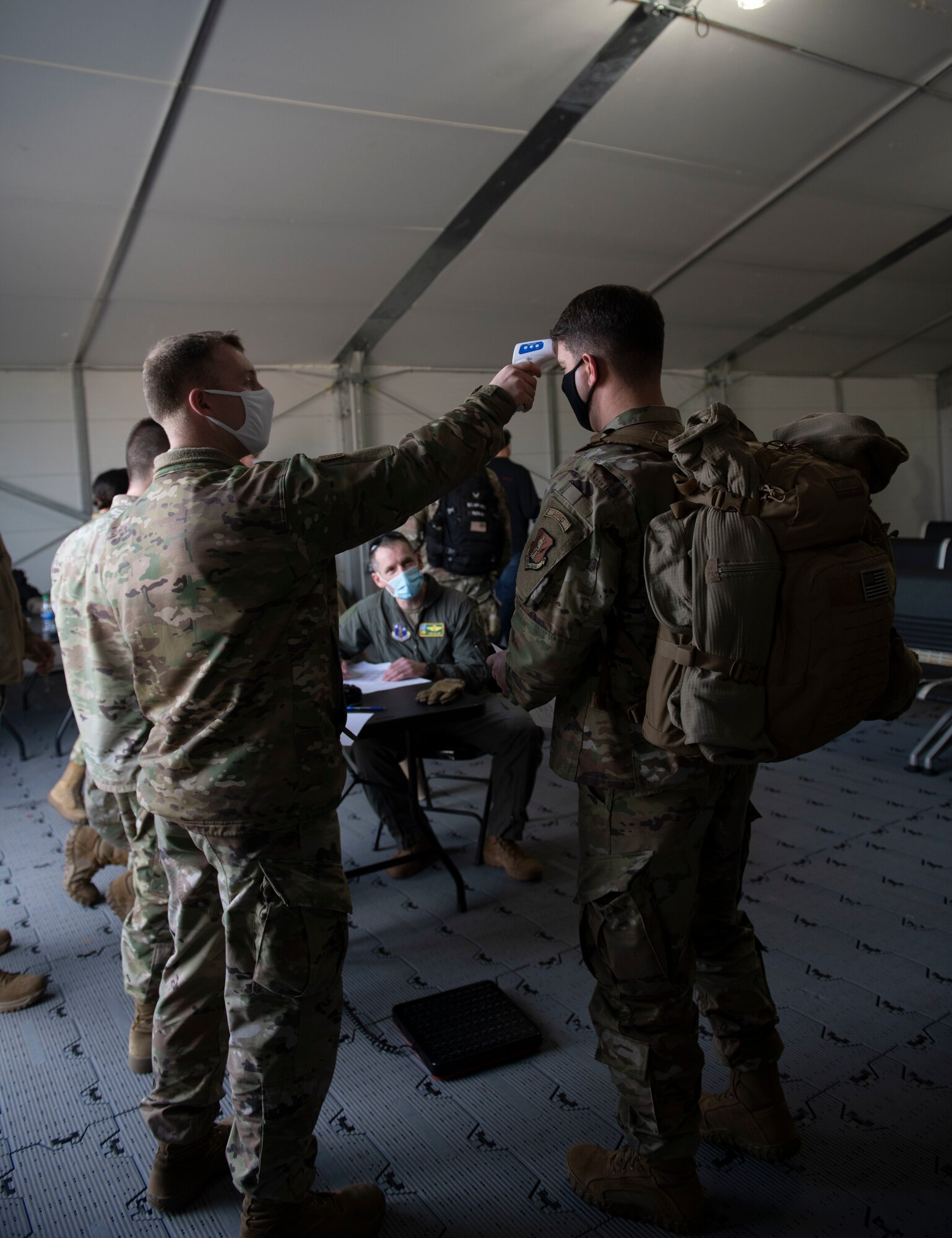 U.S. Air Force Staff Sgt. Dylan Rymer, 325th Logistics Readiness Squadron air transportation function supervisor, takes the temperature of a U.S. Air National Guardsman with the 158th Fighter Wing, Vermont National Guard on Tyndall Air Force Base, Florida, Jan. 30, 2021. In preparation to onboard a C-130 Hercules, passengers are processed with COVID-19 precaution to avoid unnecessary exposure. (U.S. Air Force photo by Airman 1st Class Tiffany Price)