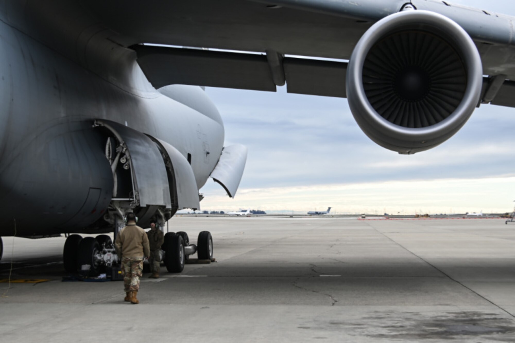 A man in a military uniform walks under the wing of a plane