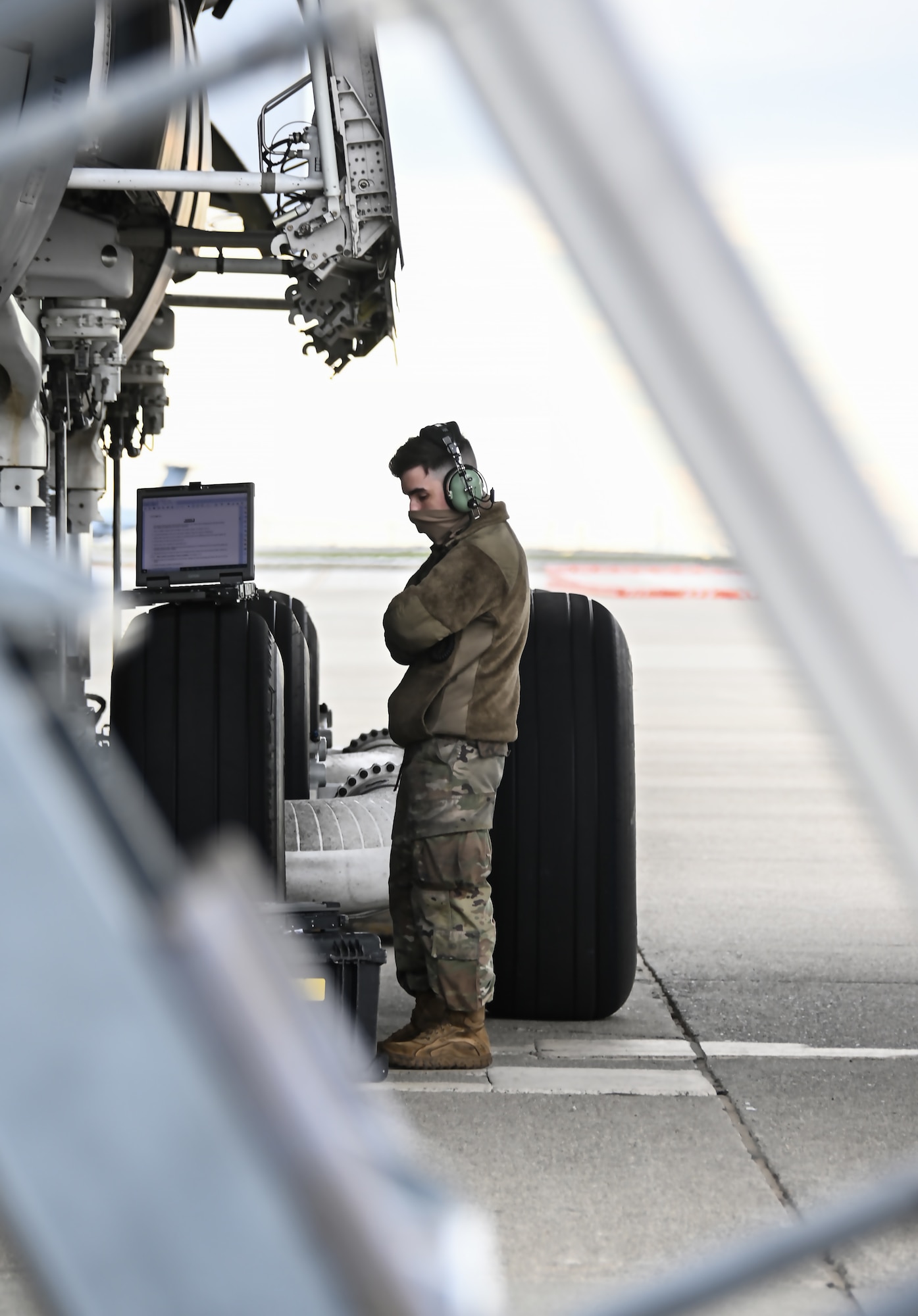 A man stands under a plane and looks at its wheels