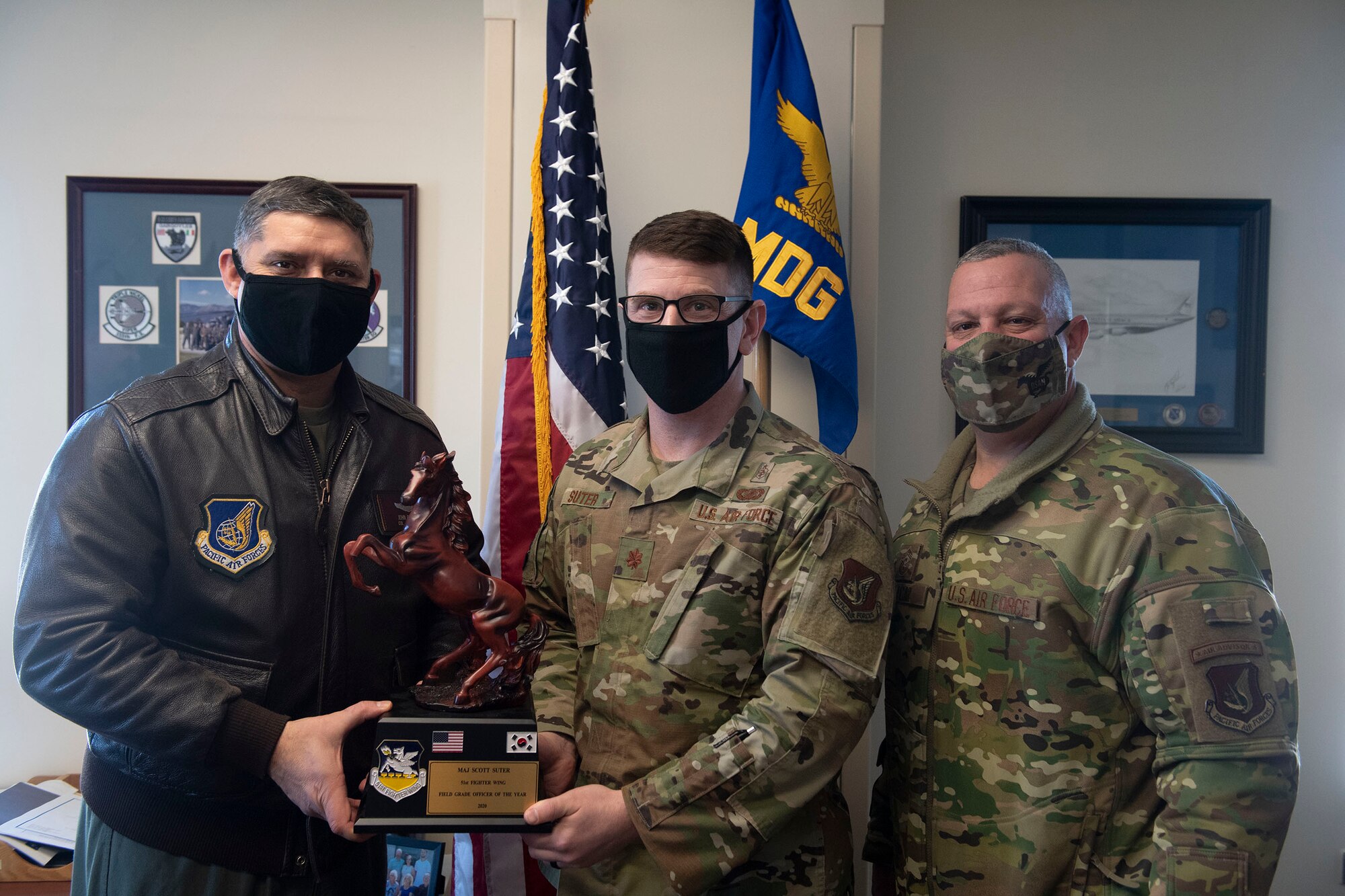 Maj. Scott Suter, 51st Medical Group, middle, receives Field Grade Officer of the Year honors from 51st Fighter Wing leadership during the 51st FW annual awards presentation, Feb. 4, 2021, at Osan Air Base, Republic of Korea. Team Osan unconventionally celebrated the ceremony by visiting the winner’s work centers to emphasize teamwork and camaraderie. (U.S. Air Force photo by Senior Airman Greg Nash)