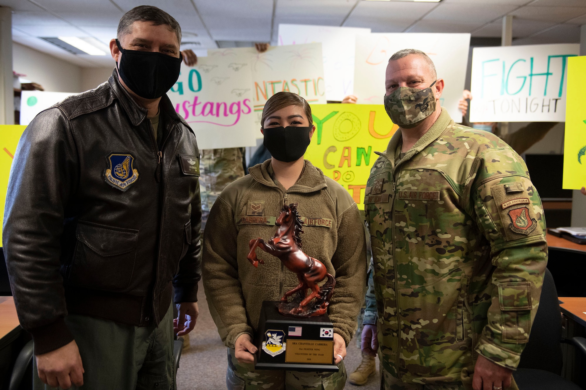 Senior Airman Chantelle Cabrera, 51st Mission Support Group, middle, receives Volunteer of the Year honors from 51st Fighter Wing leadership during the 51st FW annual awards presentation, Feb. 4, 2021, at Osan Air Base, Republic of Korea. Team Osan unconventionally celebrated the ceremony by visiting the winner’s work centers to emphasize teamwork and camaraderie. (U.S. Air Force photo by Senior Airman Greg Nash)