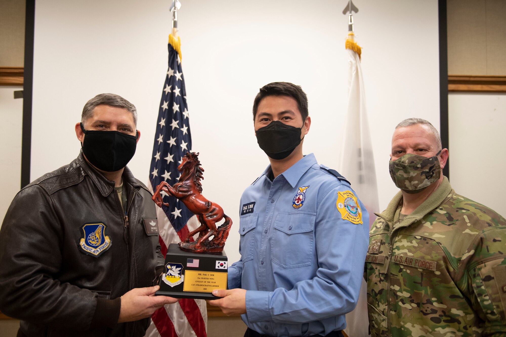 Mr. Pak u Sok, 51st Mission Support Group, middle, receives Civilian Category I of the Year honors from 51st Fighter Wing leadership during the 51st FW annual awards presentation, Feb. 4, 2021, at Osan Air Base, Republic of Korea. Team Osan unconventionally celebrated the ceremony by visiting the winner’s work centers to emphasize teamwork and camaraderie. (U.S. Air Force photo by Senior Airman Greg Nash)