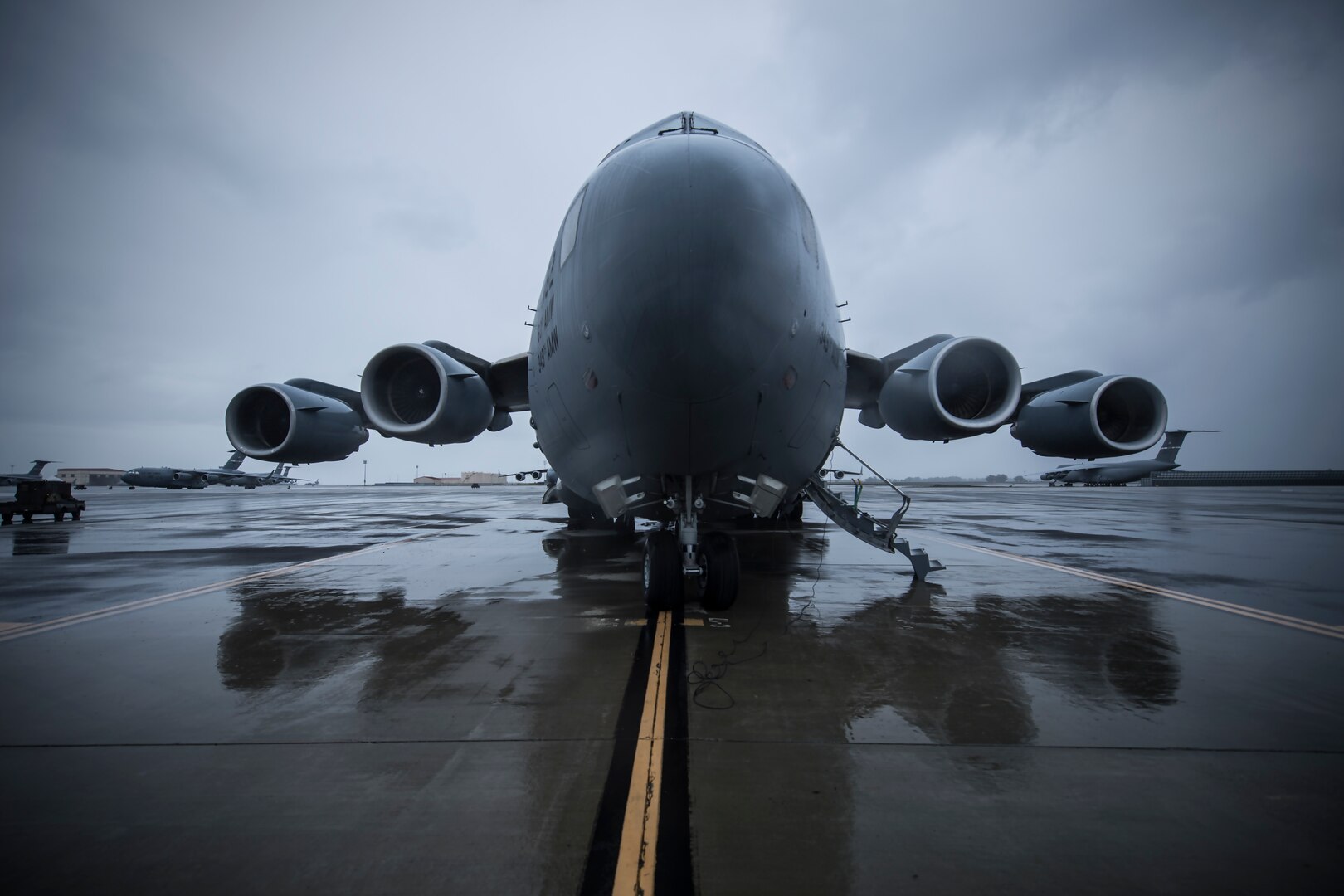 A C-17 sits on a wet flight line.