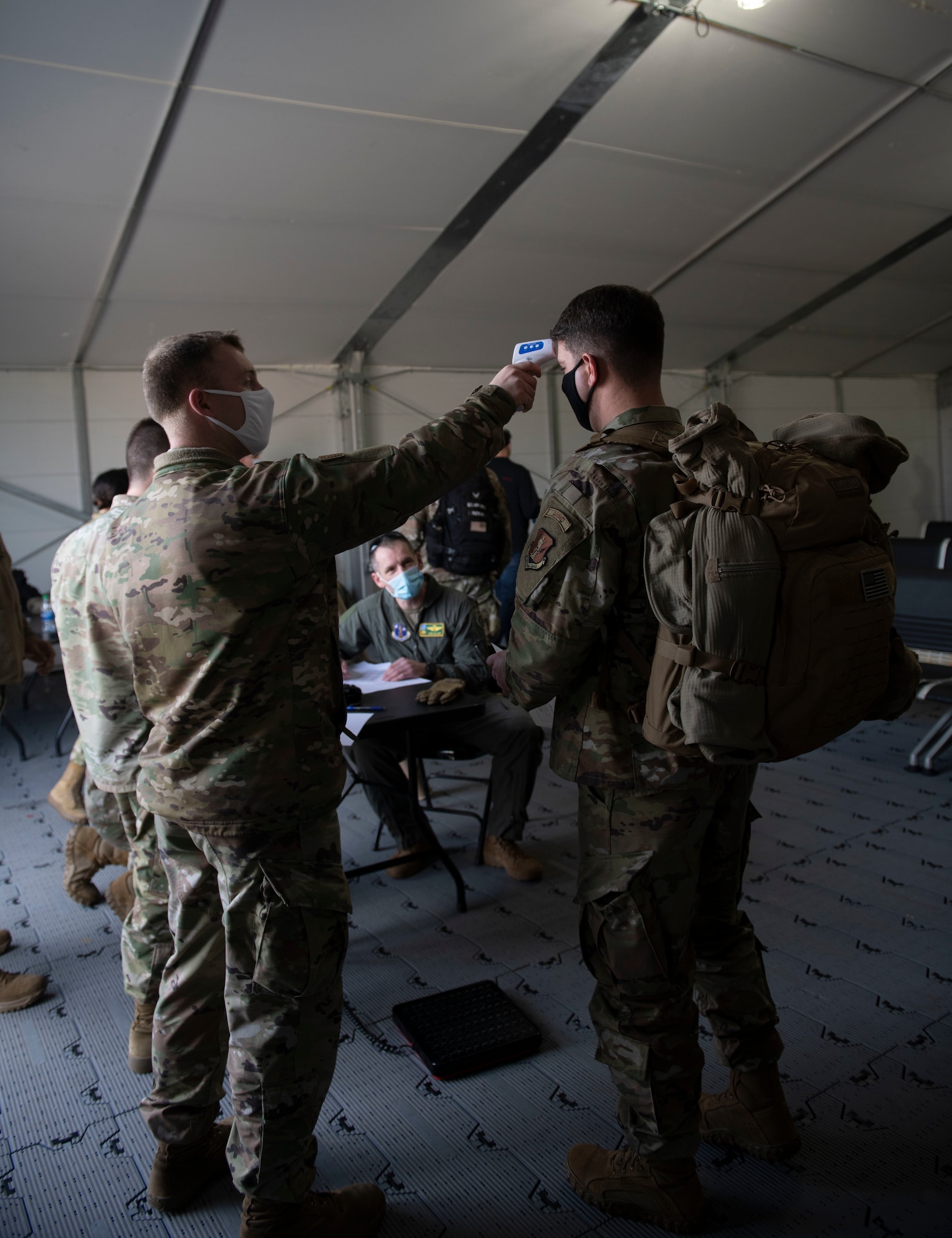 U.S. Air Force Staff Sgt. Dylan Rymer, 325th Logistics Readiness Squadron air transportation function supervisor, takes the temperature of a U.S. Air National Guardsman with the 158th Fighter Wing, Vermont National Guard on Tyndall Air Force Base, Florida, Jan. 30, 2021. In preparation to onboard a C-130 Hercules, passengers are processed with COVID-19 precaution to avoid unnecessary exposure. (U.S. Air Force photo by Airman 1st Class Tiffany Price)