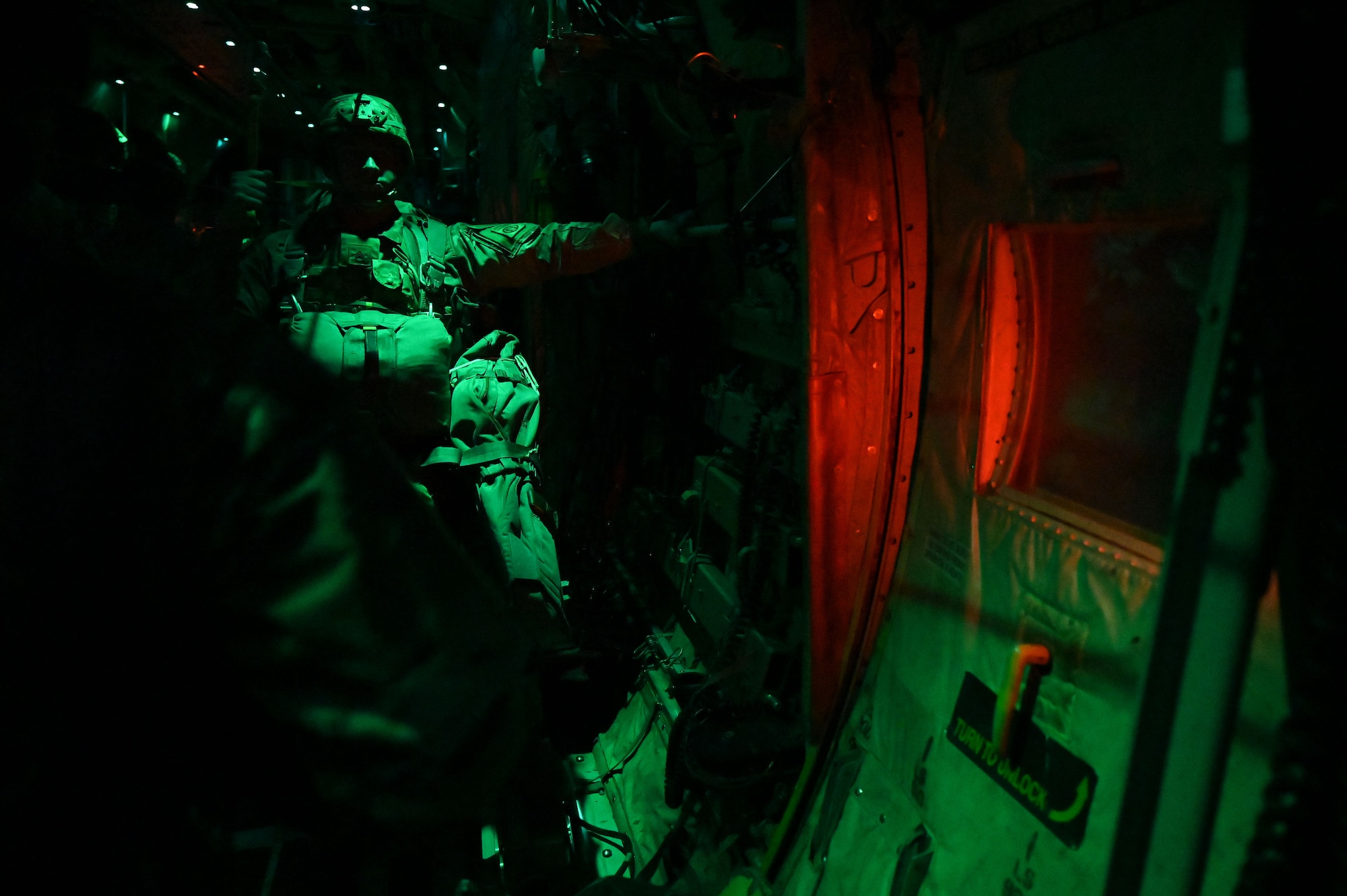 A paratrooper stands in the back of a C-130 before jumping.