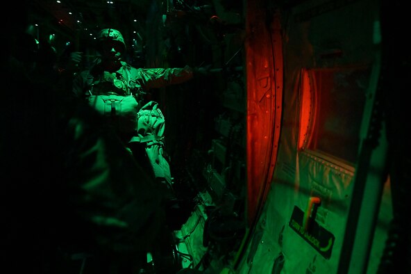 A paratrooper stands in the back of a C-130 before jumping.