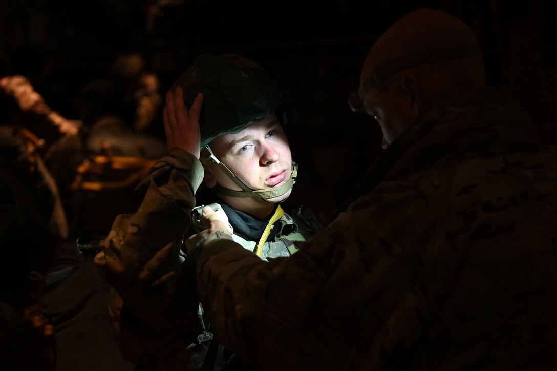 A Paratrooper puts on his helmet in the back of a C-130J