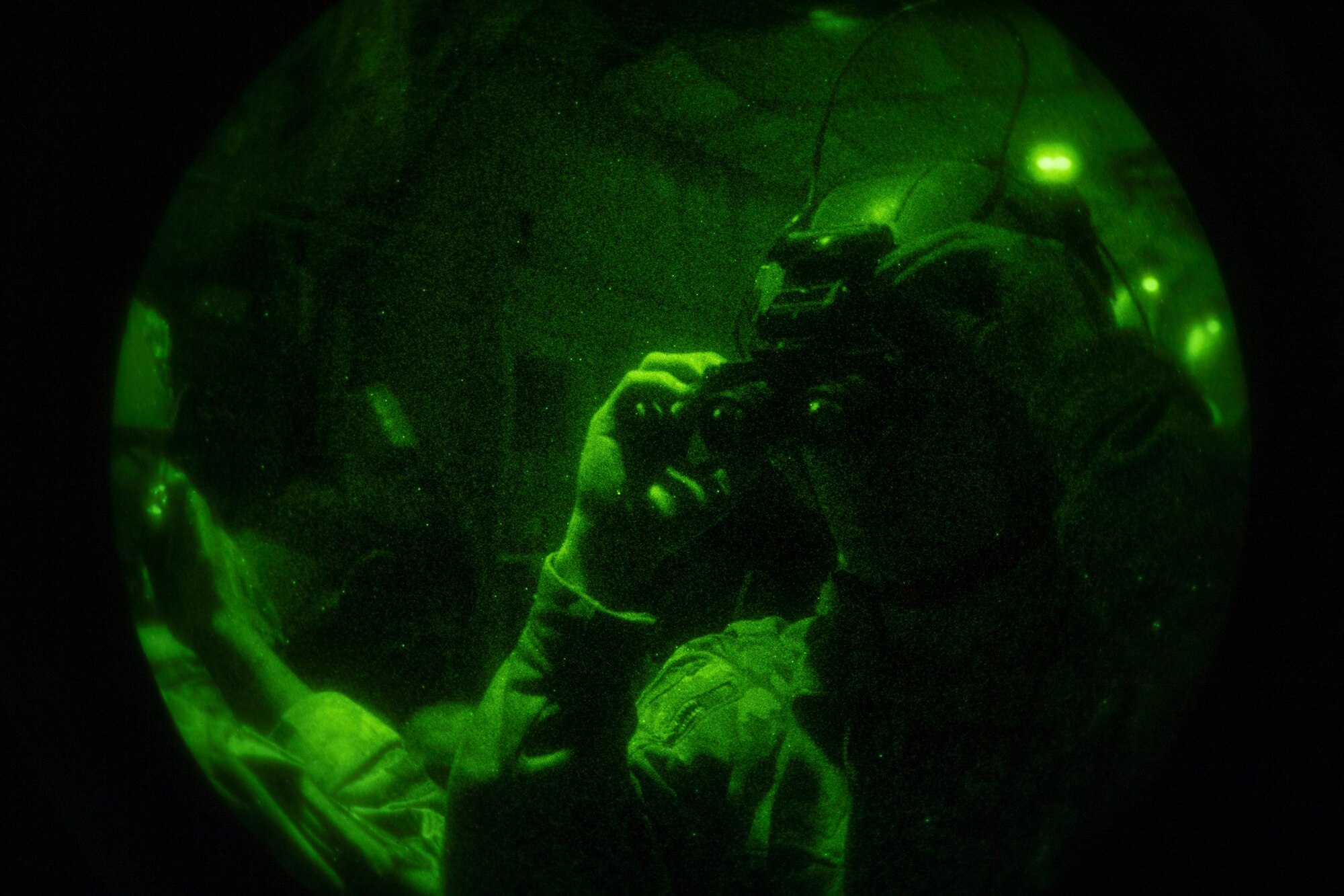 A loadmaster puts on his night vision goggles in the back of a C-130.