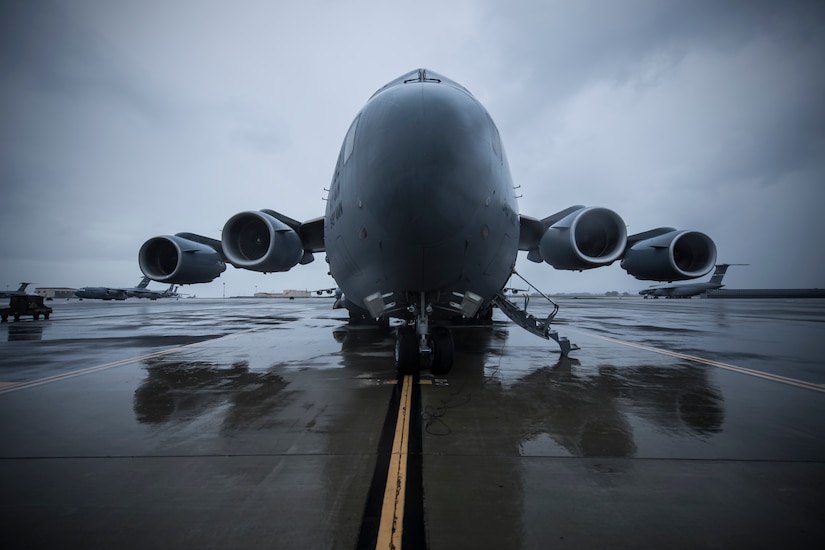 A C-17 sits on a wet flight line.