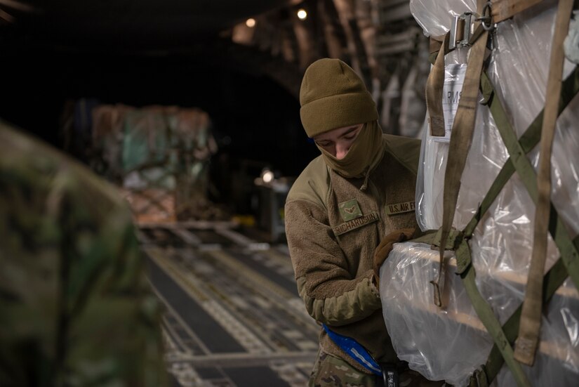 An airman is pushing a pallet inside a C-17.
