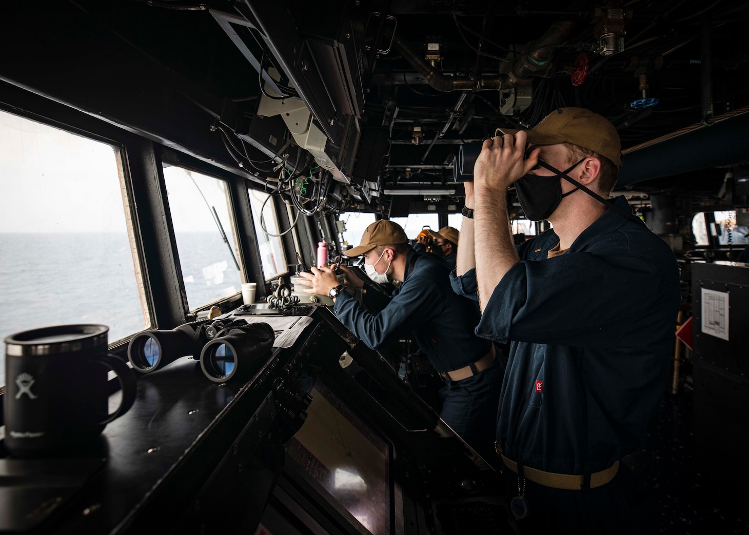 PARACEL ISLANDS, SOUTH CHINA SEA (Feb. 05, 2021) Ensign Grayson Sigler, right, from Corpus Christi, Texas, scans the horizon as Ensign Luke Dionne, from Binghamton, N.Y., looks through a telescopic alidade while standing watch in the pilot house aboard the Arleigh Burke-class guided-missile destroyer USS John S. McCain (DDG 56) as the ship conducts routine underway operations. McCain is forward-deployed to the U.S. 7th Fleet area of operations in support of security and stability in the Indo-Pacific region. (U.S. Navy photo by Mass Communication Specialist 2nd Class Markus Castaneda)