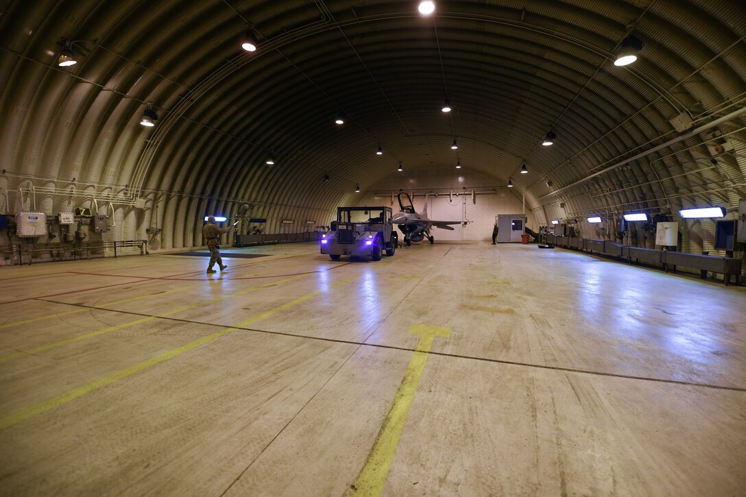 U.S. Airmen from the 31st Aircraft Maintenance Squadron tow an F-16 Fighting Falcon out of a hangar at Aviano Air Base, Italy, Feb. 1, 2021. The 31st AMXS provides diverse repair capabilities for aircraft, avionics, weapons and propulsion systems to support delivery of conventional precision-guided and special weapons. (U.S. Air Force photo by Senior Airman Ericka A. Woolever)