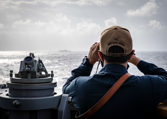 Cmdr. Joseph Gunta, the executive officer of the Arleigh Burke-class guided-missile destroyer USS John S. McCain (DDG 56) observes a surface contact from the bridge wing.