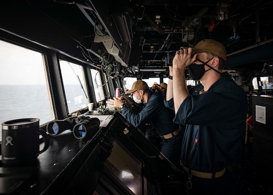 PARACEL ISLANDS, SOUTH CHINA SEA (Feb. 05, 2021) Ensign Grayson Sigler, right, from Corpus Christi, Texas, scans the horizon as Ensign Luke Dionne, from Binghamton, N.Y., looks through a telescopic alidade while standing watch in the pilot house aboard the Arleigh Burke-class guided-missile destroyer USS John S. McCain (DDG 56) as the ship conducts routine underway operations. McCain is forward-deployed to the U.S. 7th Fleet area of operations in support of security and stability in the Indo-Pacific region. (U.S. Navy photo by Mass Communication Specialist 2nd Class Markus Castaneda)
