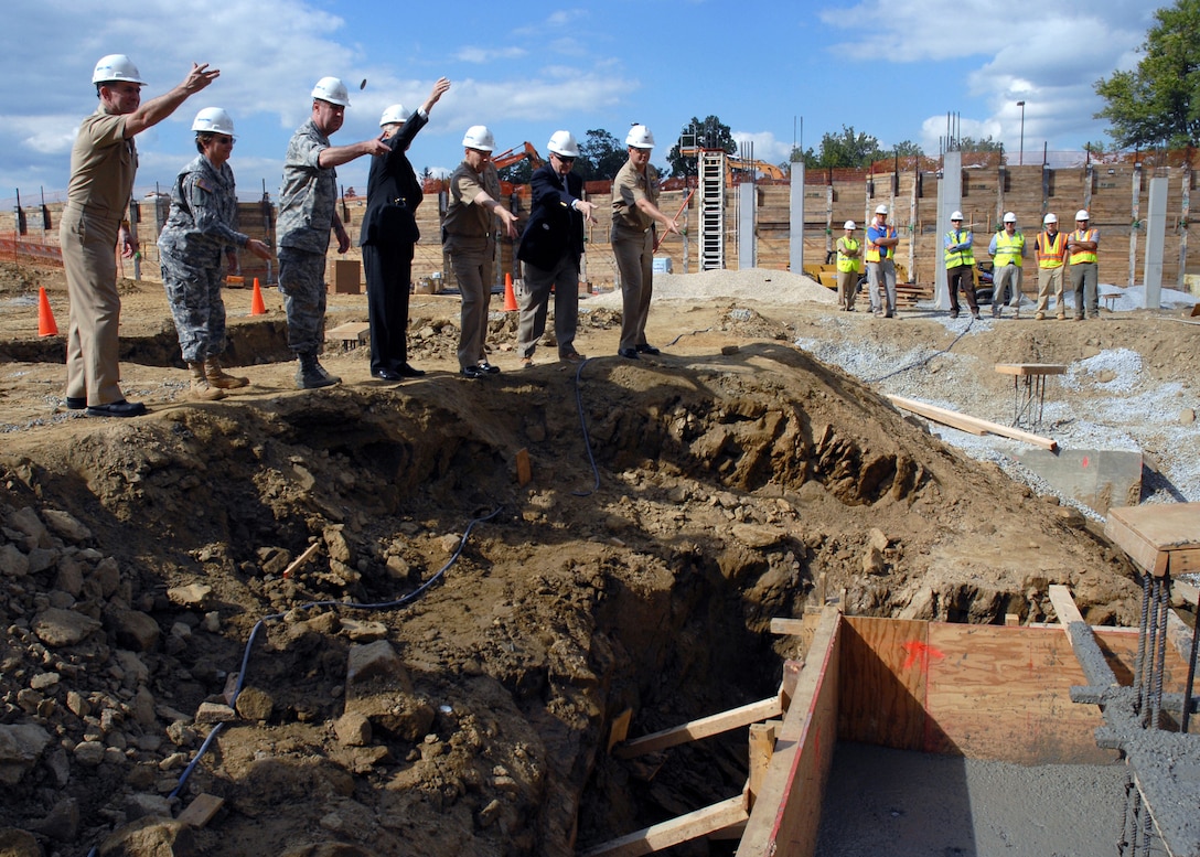 Several people follow through on a traditional coin toss into a chasm at a construction site.