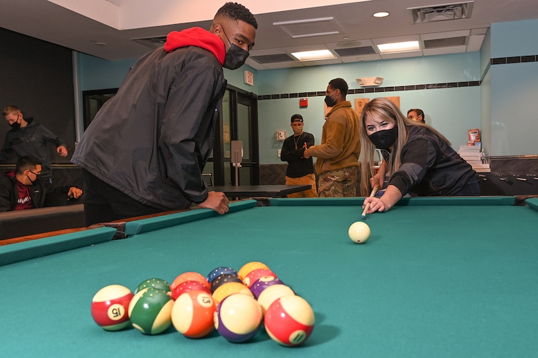 Senior Airman Alexandra Berumen, dorm council president, plays pool while Airman 1st Class Jachin Henderson, dorm council secretary, looks on, during the grand opening event of the Minuteman Escape at Hanscom Air Force Base, Mass., Dec. 16. Dorm residents recently elected five new council members to serve as the liaison between residents and base leaders through November. (U.S. Air Force photo by Todd Maki)