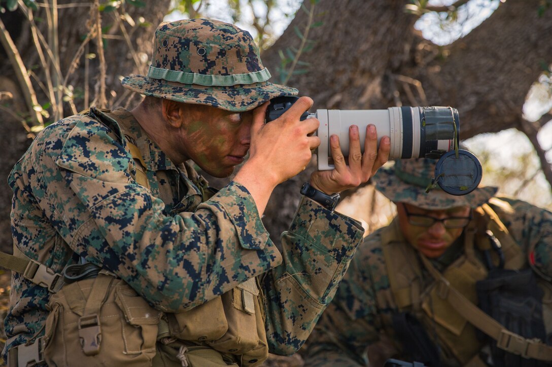 U.S. Marine Corps Lance Cpl. Collin Cummins, left, a radio reconnaissance team point man with 1st Radio Battalion (RADBN), I Marine Expeditionary Force Information Group, photographs simulated enemy activity from a concealed position during a certification exercise at Marine Corps Base Camp Pendleton, California, Oct. 1, 2020. The certification exercise tested 1st RADBN’s ability to conduct tactical recovery of aircraft personnel, radio reconnaissance, and various signals intelligence exercises. (U.S. Marine Corps photo by Lance Cpl. Ian M. Simmons)